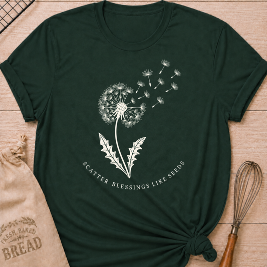 Forest green women's relaxed fit t-shirt with a dandelion releasing its seeds and the words Scatter Blessings Like Seeds.