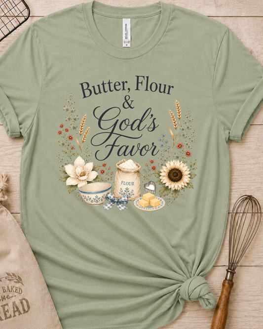 Sage green women's relaxed fit t-shirt reading Butter, Flour and God's Favor, framed by a flour sack, a mixing bowl, butter, a sunflower, and wildflowers.