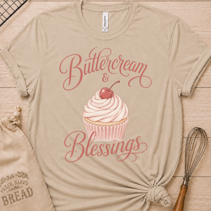 Heather stone women's relaxed fit t-shirt reading Buttercream and Blessings with a frosted cupcake and a delicate bow.