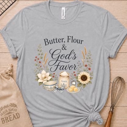 Athletic heather women's relaxed fit t-shirt reading Butter, Flour and God's Favor, framed by a flour sack, a mixing bowl, butter, a sunflower, and wildflowers.