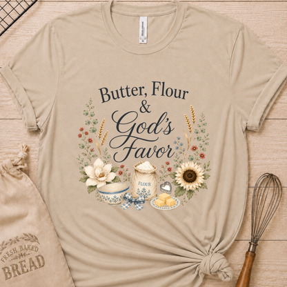 Heather stone women's relaxed fit t-shirt reading Butter, Flour and God's Favor, framed by a flour sack, a mixing bowl, butter, a sunflower, and wildflowers.