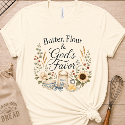 Natural cream women's relaxed fit t-shirt reading Butter, Flour and God's Favor, framed by a flour sack, a mixing bowl, butter, a sunflower, and wildflowers.
