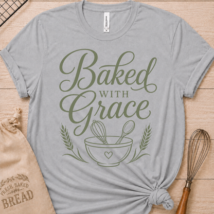 Athletic heather women's relaxed fit t-shirt with Baked with Grace in green script above a mixing bowl with a whisk and wooden spoon.