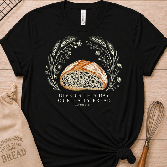 Black women's relaxed fit t-shirt with the Daily Bread design featuring a rustic loaf of bread wreathed in wheat and flowers, inspired by Matthew 6:11.