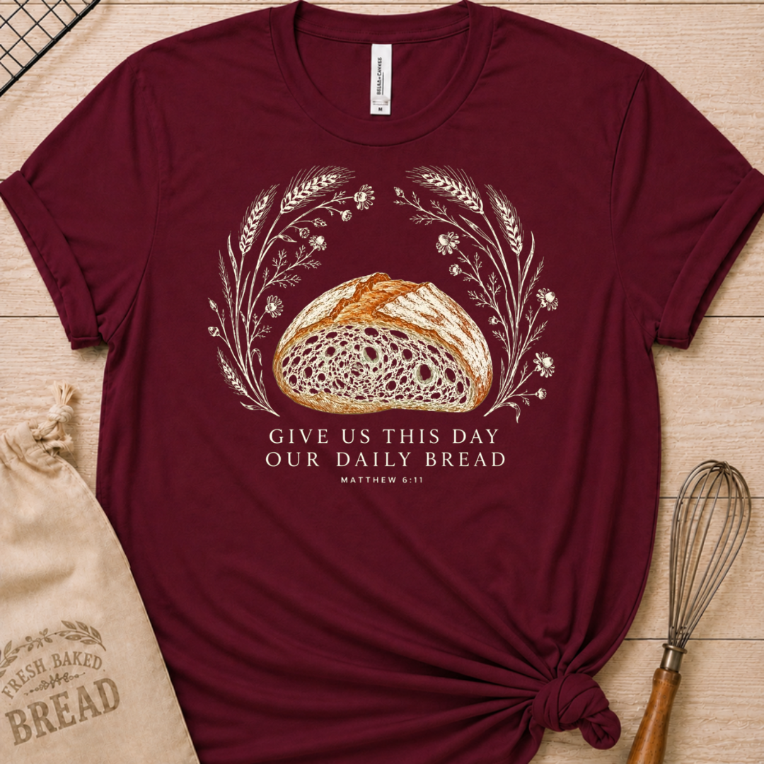 Maroon women's relaxed fit t-shirt with the Daily Bread design featuring a rustic loaf of bread wreathed in wheat and flowers, inspired by Matthew 6:11.