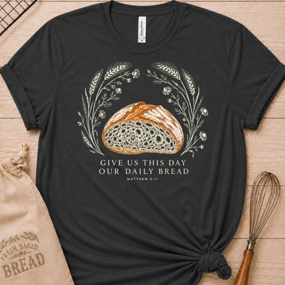 Dark heather grey women's relaxed fit t-shirt with the Daily Bread design featuring a rustic loaf of bread wreathed in wheat and flowers, inspired by Matthew 6:11.