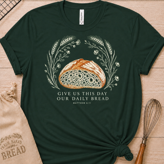 Forest green women's relaxed fit t-shirt with the Daily Bread design featuring a rustic loaf of bread wreathed in wheat and flowers, inspired by Matthew 6:11.