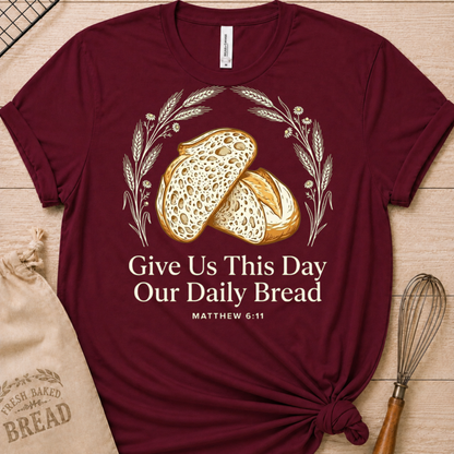 Maroon women's relaxed fit t-shirt with the Daily Bread design featuring two rustic half loaves side by side, inspired by Matthew 6:11.