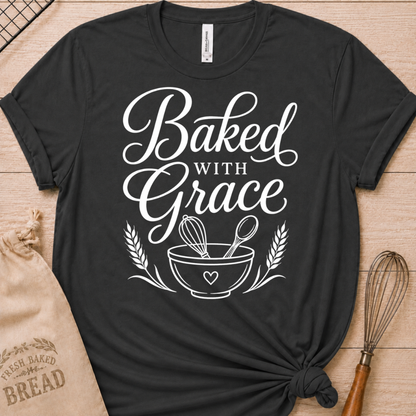 Dark heather grey women's relaxed fit t-shirt with Baked with Grace in white script above a mixing bowl with a whisk and wooden spoon.