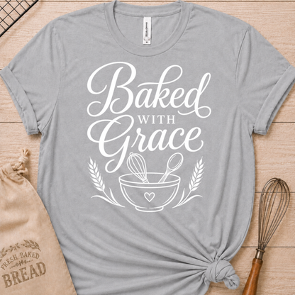 Athletic heather women's relaxed fit t-shirt with Baked with Grace in white script above a mixing bowl with a whisk and wooden spoon.