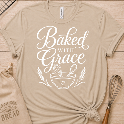 Heather stone women's relaxed fit t-shirt with Baked with Grace in white script above a mixing bowl with a whisk and wooden spoon.