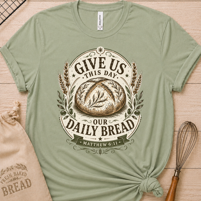 Sage green women's relaxed fit t-shirt with the Daily Bread emblem printed in cream, a clean badge-style bread illustration inspired by Matthew 6:11.