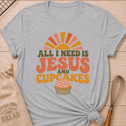 Athletic Heather All I Need Is Jesus and Cupcakes women's relaxed fit tee with retro lettering and a pink frosted cupcake in warm sunrise colors