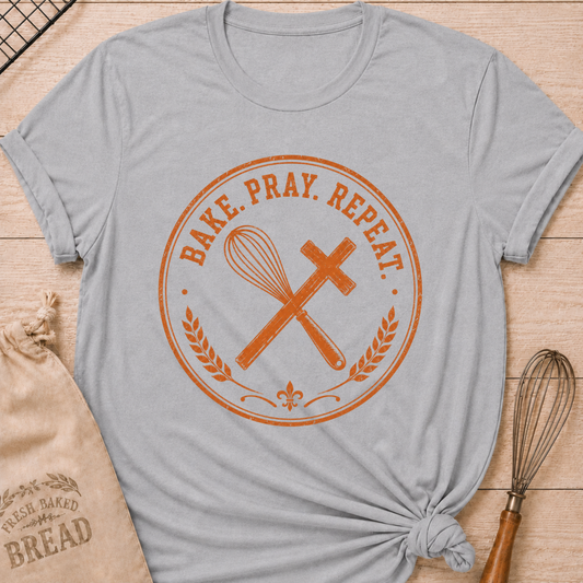 Athletic heather women's relaxed fit t-shirt with the words Bake. Pray. Repeat. inside a vintage bakery emblem with a classic whisk, a rolling pin, and wheat details.