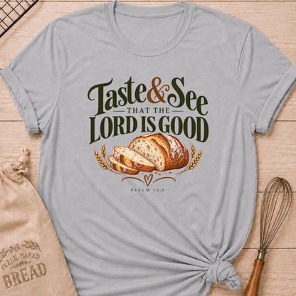 Athletic Heather women's relaxed fit tee with bold vintage Taste and See That the Lord Is Good lettering above a sliced artisan loaf, golden wheat, and Psalm 34:8