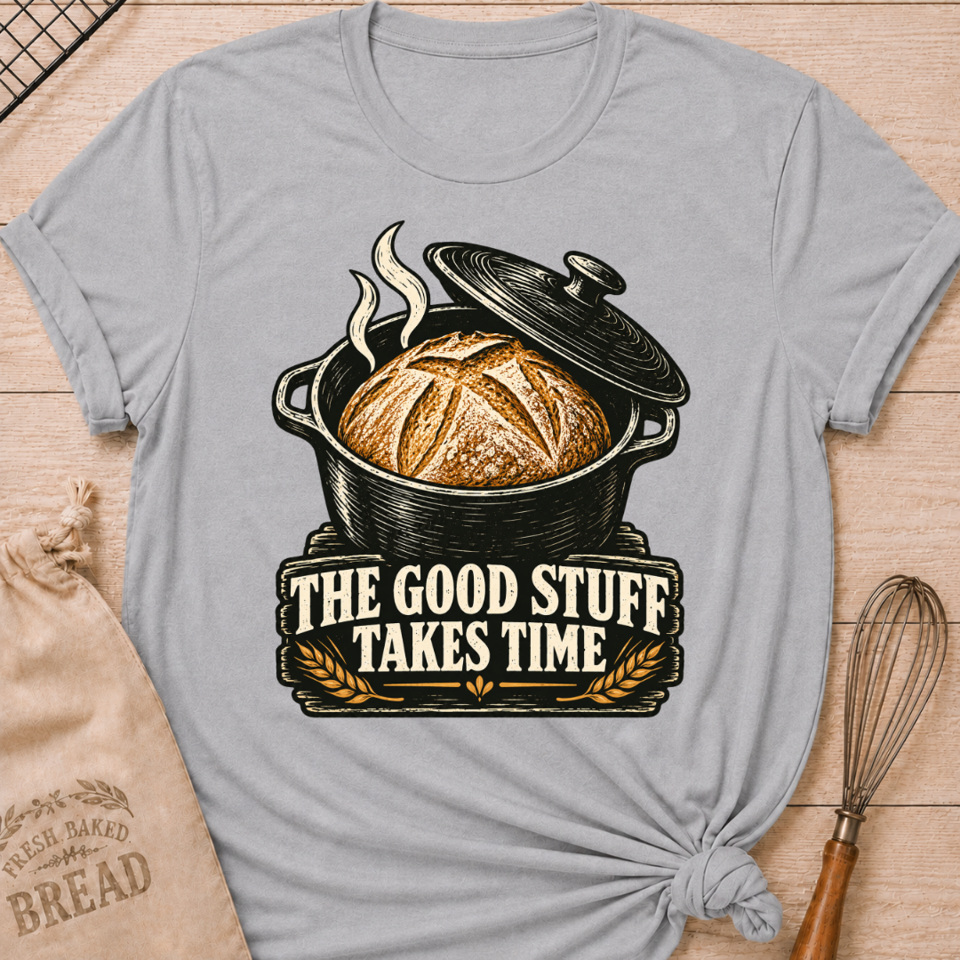 Athletic Heather women's relaxed fit tee with a golden artisan loaf rising from a vintage Dutch oven, steam curling overhead and wheat accents below, with The Good Stuff Takes Time lettering
