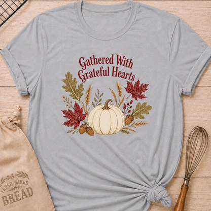 Athletic Heather women's relaxed fit tee with Gathered With Grateful Hearts lettering above a soft ivory pumpkin surrounded by wheat, acorns, berries and richly colored autumn leaves