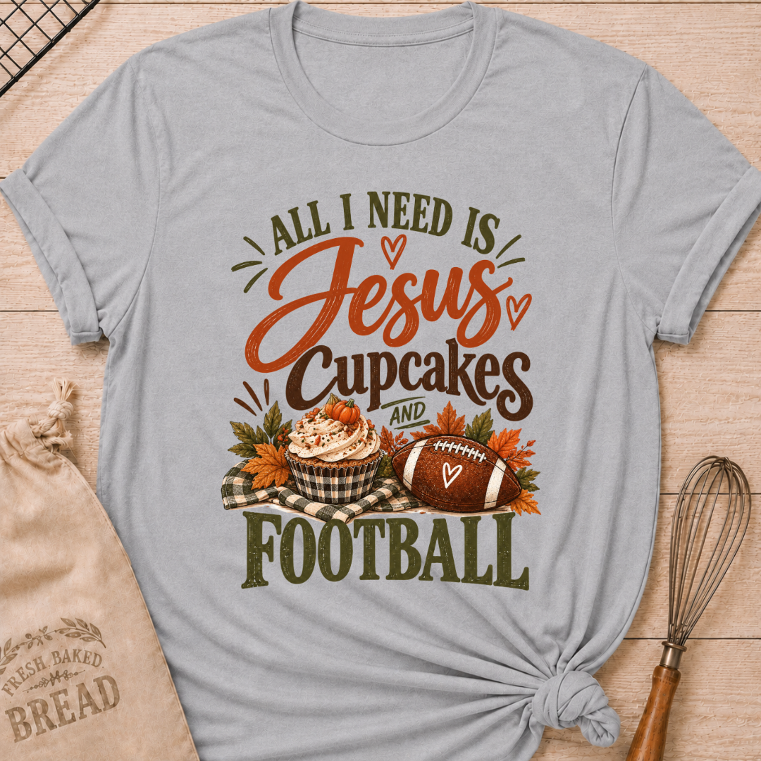Athletic Heather women's relaxed fit tee with bold vintage All I Need Is Jesus, Cupcakes and Football lettering, a pumpkin topped cupcake, autumn leaves and a football on a gingham blanket