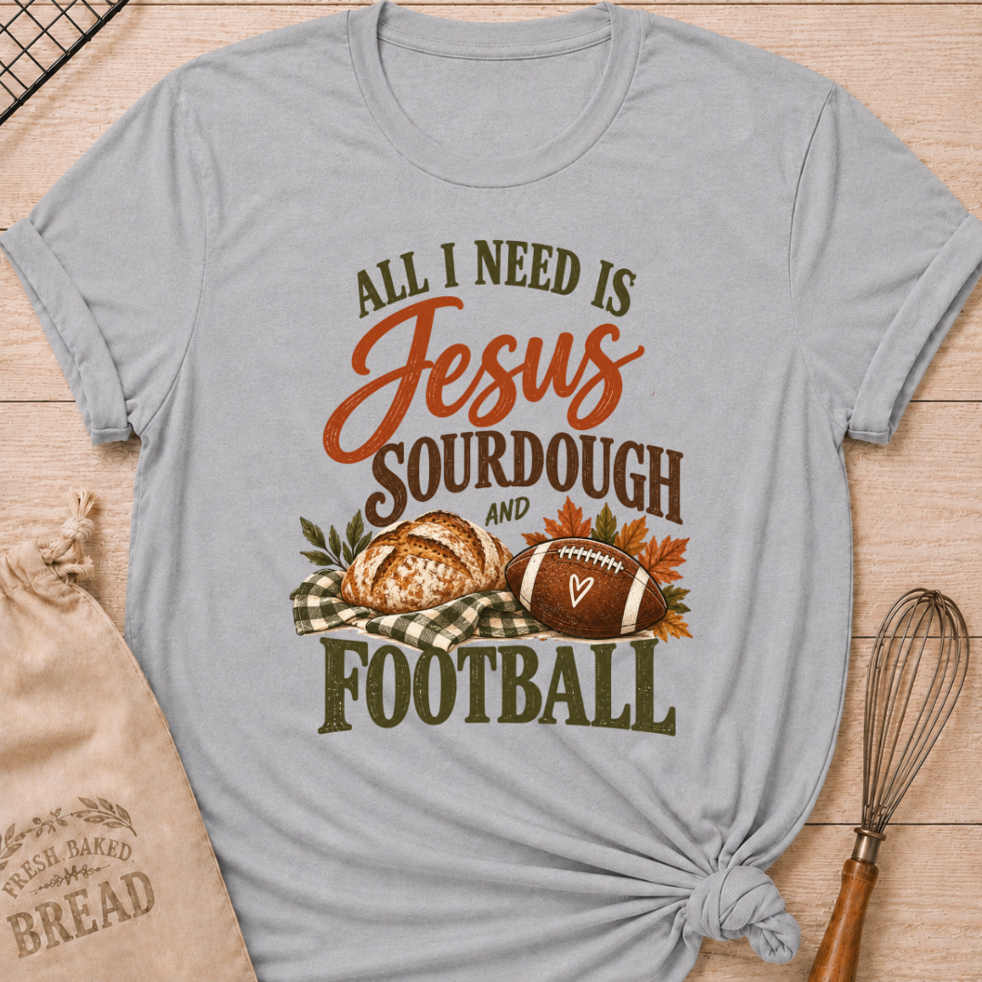Athletic Heather women's relaxed fit tee with bold vintage All I Need Is Jesus, Sourdough and Football lettering, a rustic sourdough loaf, classic football, gingham accents and autumn leaves in rich harvest tones