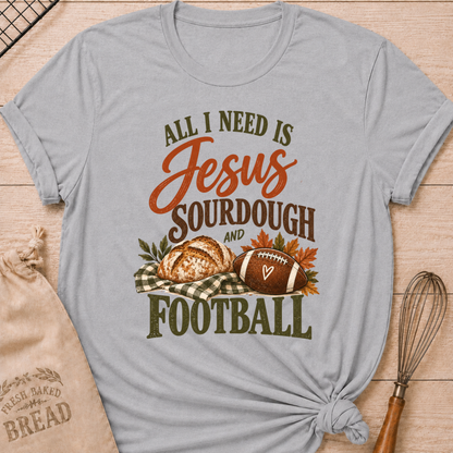 Athletic Heather women's relaxed fit tee with bold vintage All I Need Is Jesus, Sourdough and Football lettering, a rustic sourdough loaf, classic football, gingham accents and autumn leaves in rich harvest tones