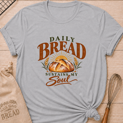 Athletic Heather women's relaxed fit tee with Daily Bread Sustains My Soul lettering around a golden artisan loaf beneath a rising sun, framed by wheat in rich earthy tones