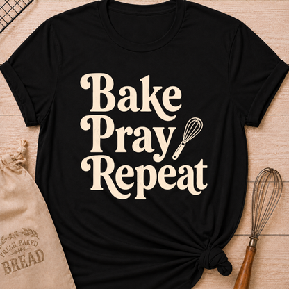 Black women's relaxed fit t-shirt with the words Bake, Pray, Repeat in playful vintage lettering and a classic kitchen whisk.