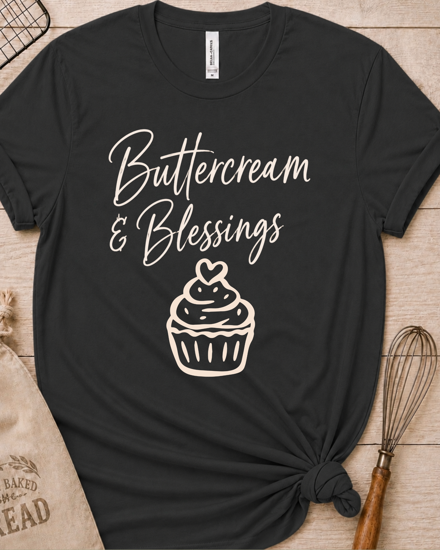Dark heather grey women's relaxed fit t-shirt with Buttercream and Blessings in flowing script above a cupcake topped with a heart.