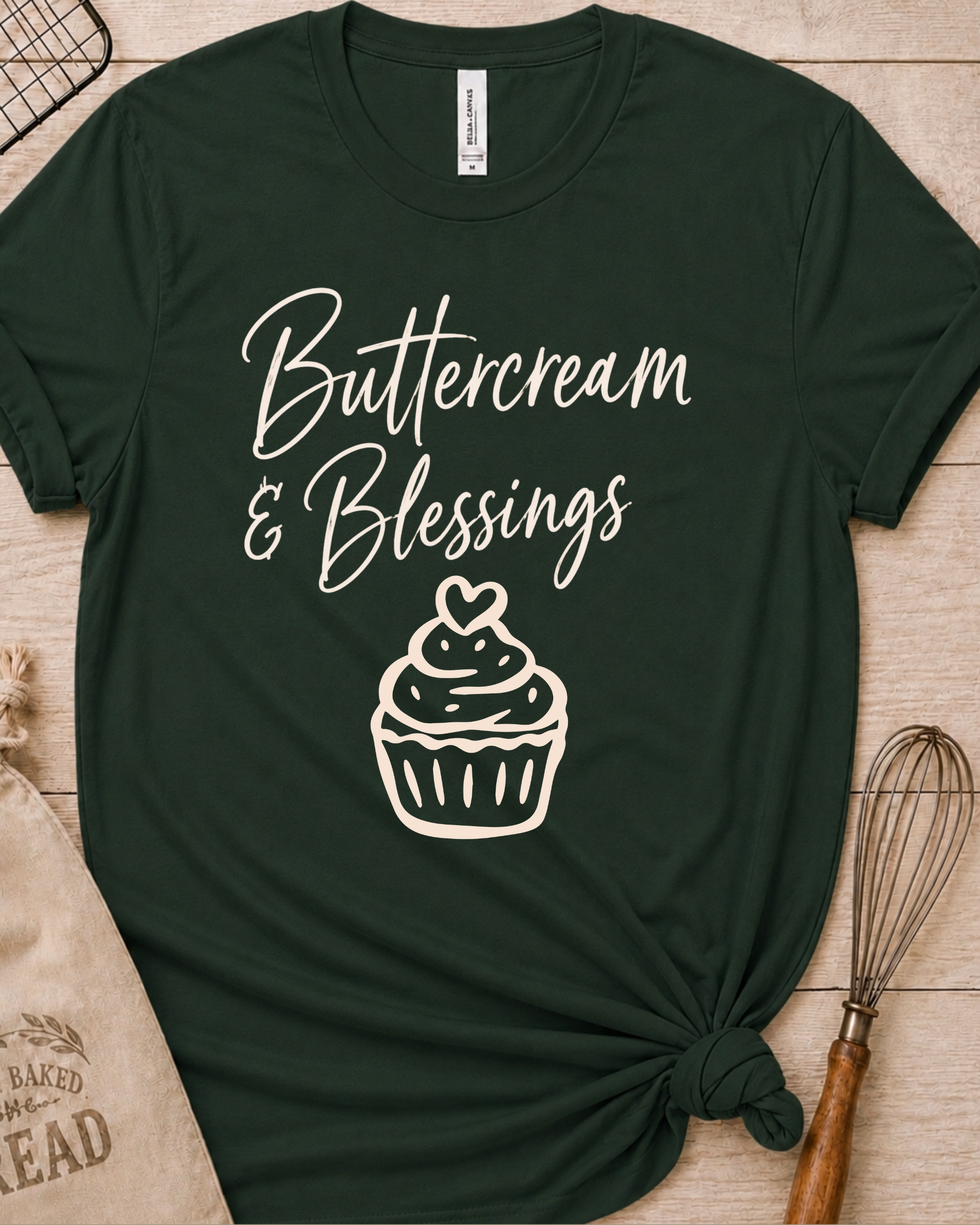 Forest green women's relaxed fit t-shirt with Buttercream and Blessings in flowing script above a cupcake topped with a heart.