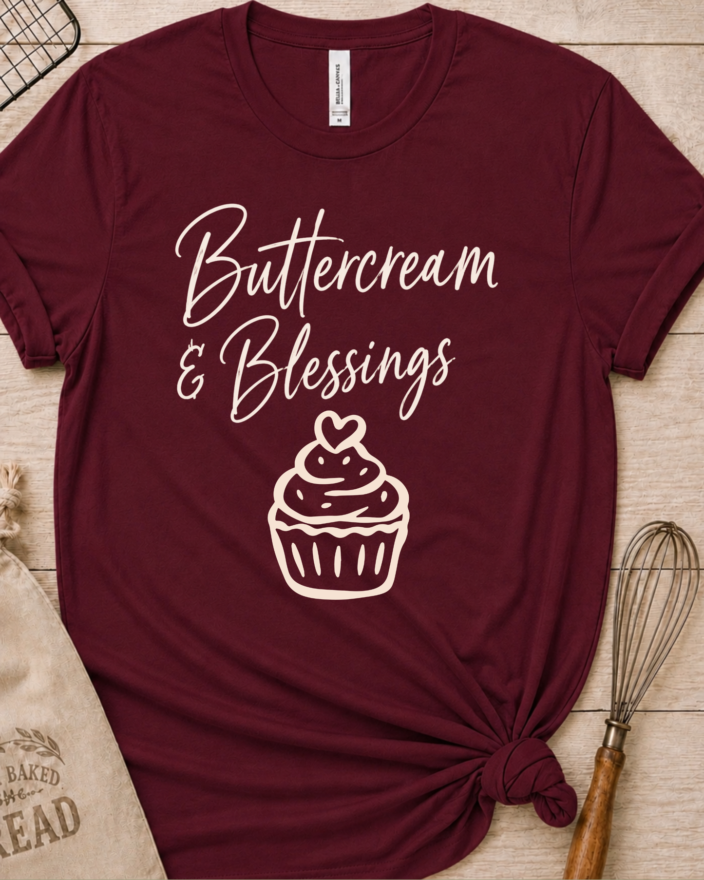 Maroon women's relaxed fit t-shirt with Buttercream and Blessings in flowing script above a cupcake topped with a heart.
