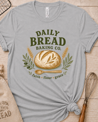 Heather grey women's relaxed fit t-shirt with the Daily Bread Baking Co. design, a retro bakery emblem featuring an artisan bread loaf, wheat stalks, and a wooden spoon above the words faith, flour, grace.