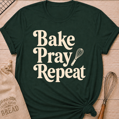 Forest green women's relaxed fit t-shirt with the words Bake, Pray, Repeat in playful vintage lettering and a classic kitchen whisk.