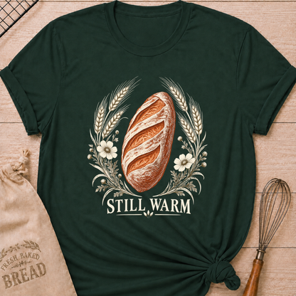 Forest Green women's relaxed fit tee with a freshly baked artisan loaf framed by wheat and soft wildflowers in an old world engraved style, with Still Warm lettering