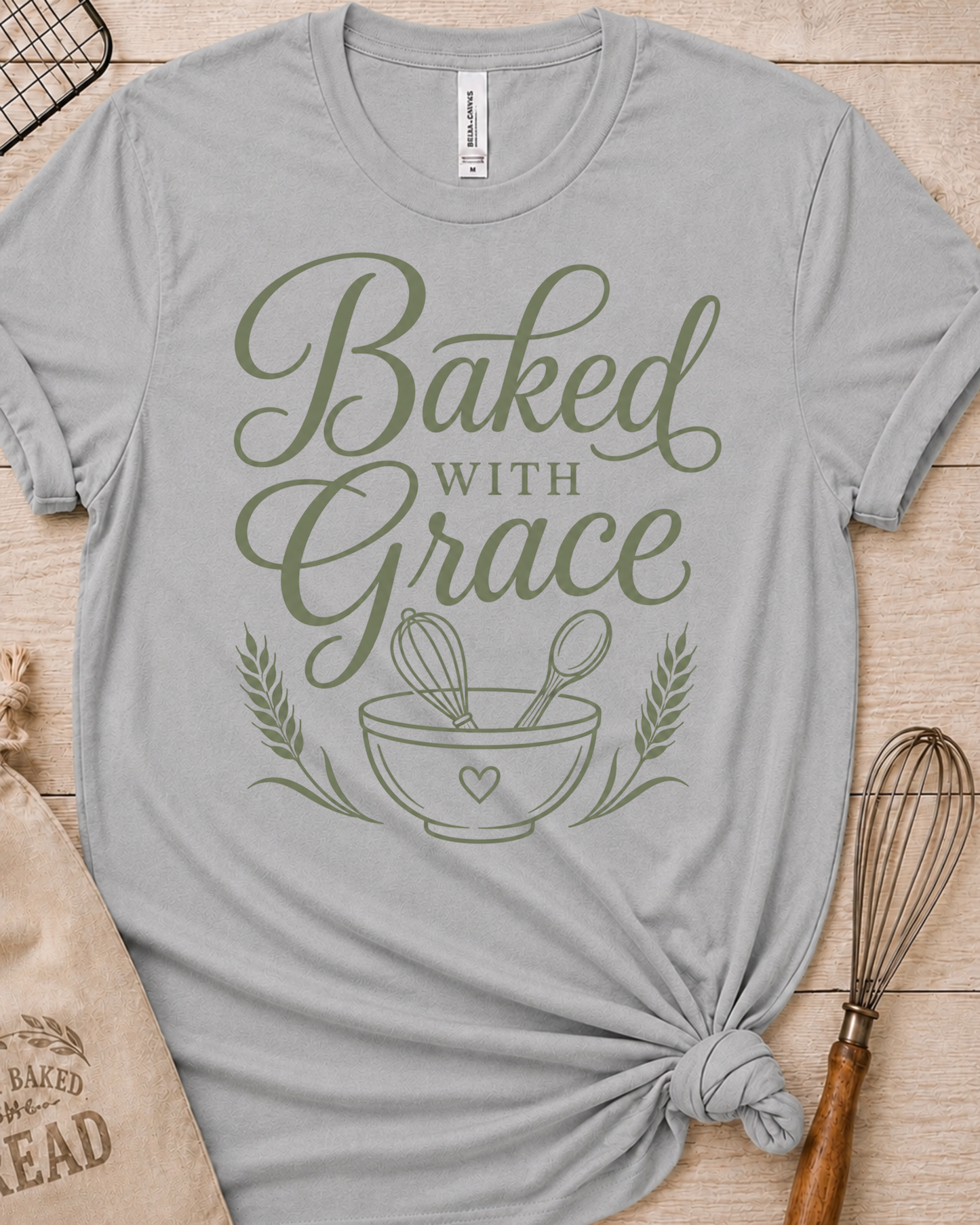Heather grey women's relaxed fit t-shirt with Baked with Grace in green script above a mixing bowl with a whisk and wooden spoon.