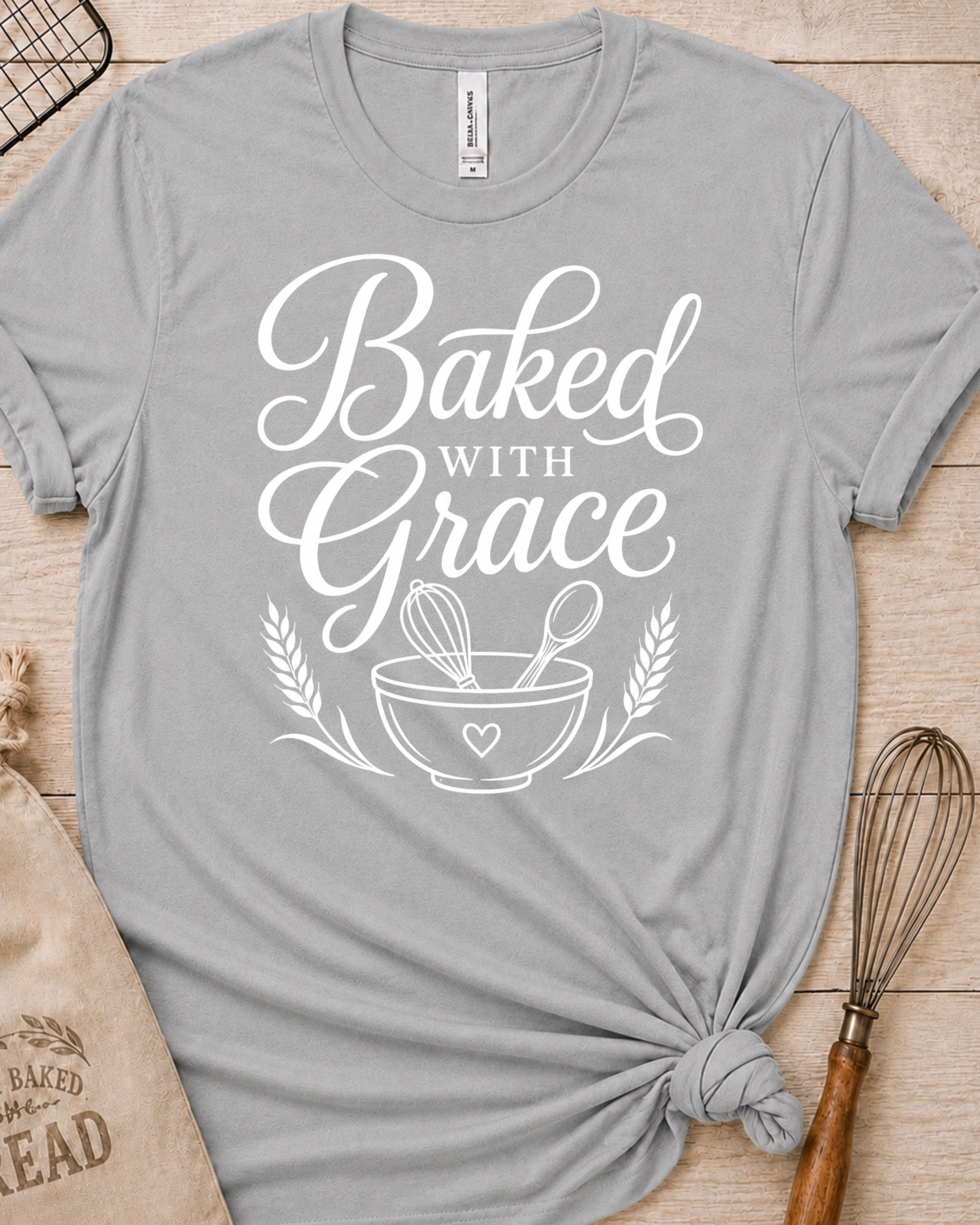 Heather grey women's relaxed fit t-shirt with Baked with Grace in white script above a mixing bowl with a whisk and wooden spoon.