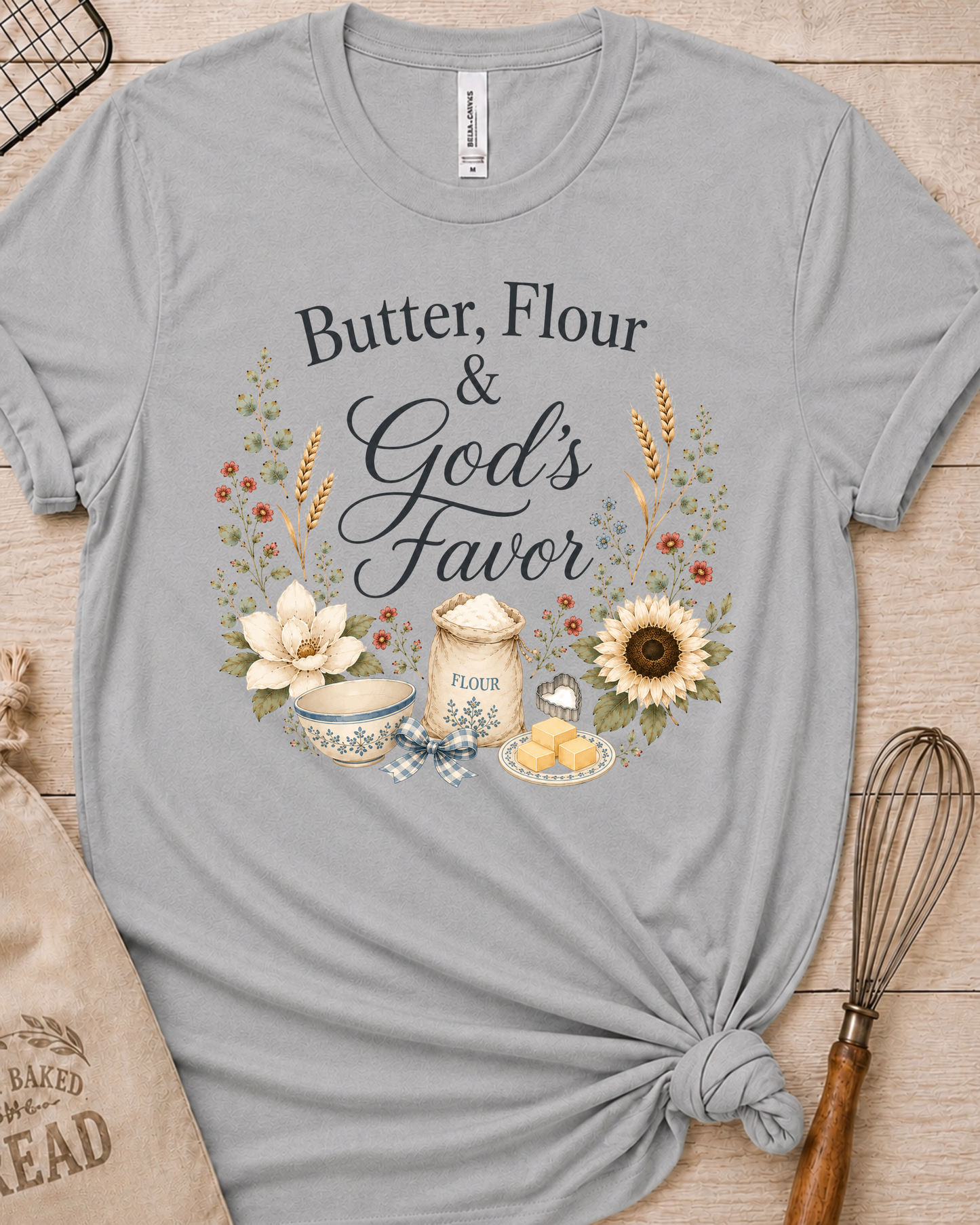 Heather grey women's relaxed fit t-shirt reading Butter, Flour and God's Favor, framed by a flour sack, a mixing bowl, butter, a sunflower, and wildflowers.