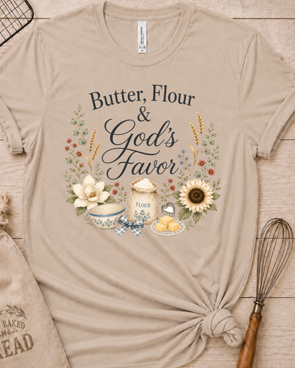 Heather stone women's relaxed fit t-shirt reading Butter, Flour and God's Favor, framed by a flour sack, a mixing bowl, butter, a sunflower, and wildflowers.