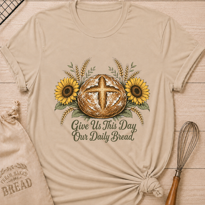 Heather Stone women's relaxed fit tee with a rustic sourdough loaf, golden wheat, and yellow sunflowers, reading Give Us This Day Our Daily Bread