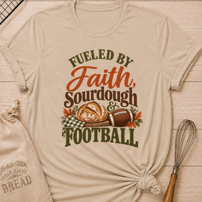 Heather Stone women's relaxed fit tee with bold vintage Fueled by Faith Sourdough and Football lettering, a rustic sourdough loaf, classic football, gingham accents and autumn leaves