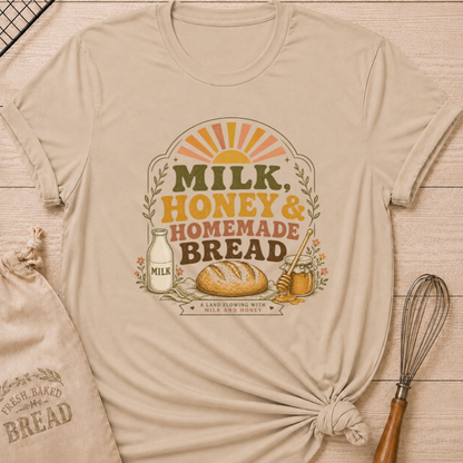 Heather stone women's relaxed fit t-shirt with the words Milk, Honey & Homemade Bread in vintage lettering with a rustic loaf, an old-fashioned milk bottle, and a jar of honey beneath a retro sunrise.