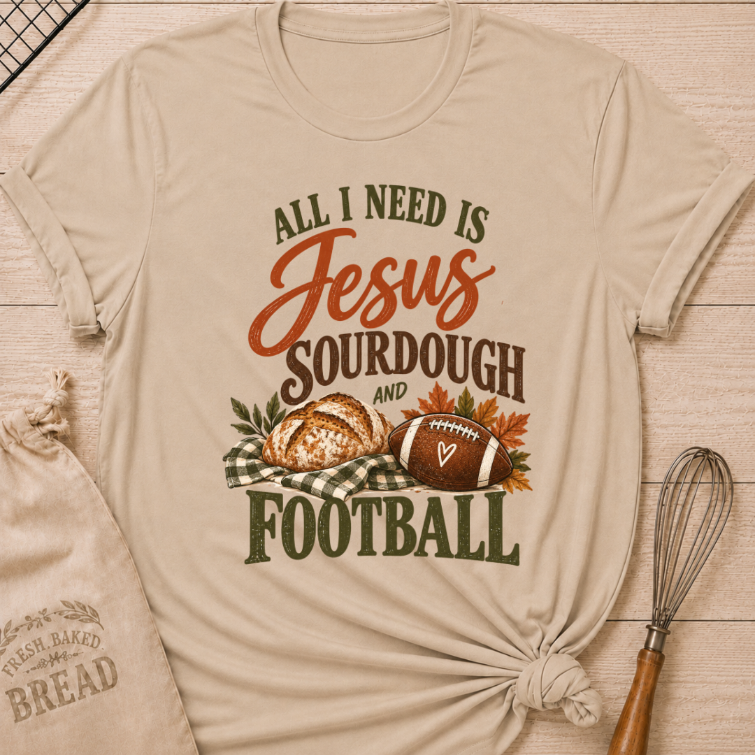 Heather Stone women's relaxed fit tee with bold vintage All I Need Is Jesus, Sourdough and Football lettering, a rustic sourdough loaf, classic football, gingham accents and autumn leaves in rich harvest tones