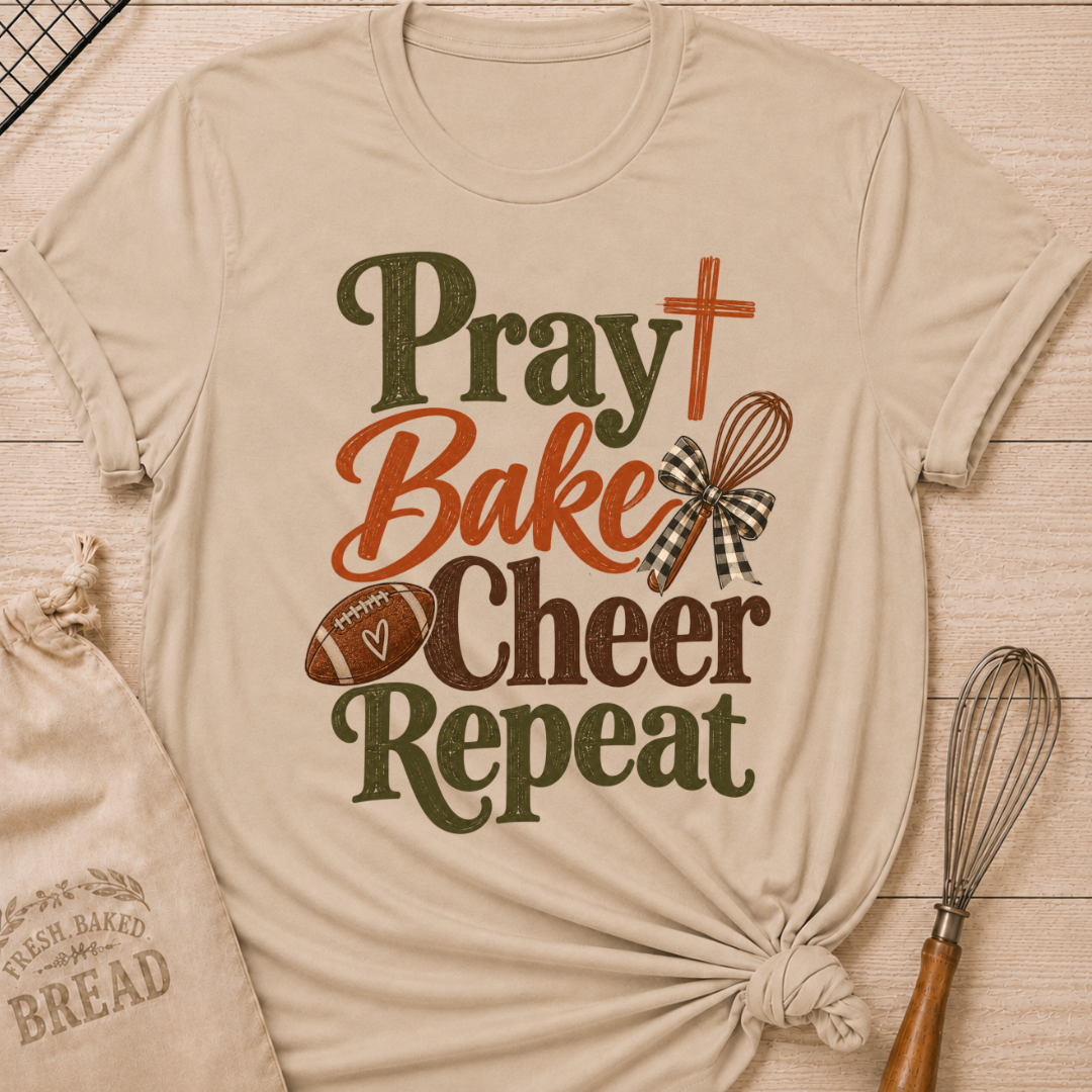 Heather Stone women's relaxed fit tee with bold vintage Pray Bake Cheer Repeat lettering, a football, whisk, cross and gingham bow in warm autumn tones
