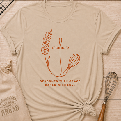 Heather stone women's relaxed fit t-shirt with the words Seasoned With Grace, Baked With Love in clean line art with wheat, a subtle cross, and a classic whisk.