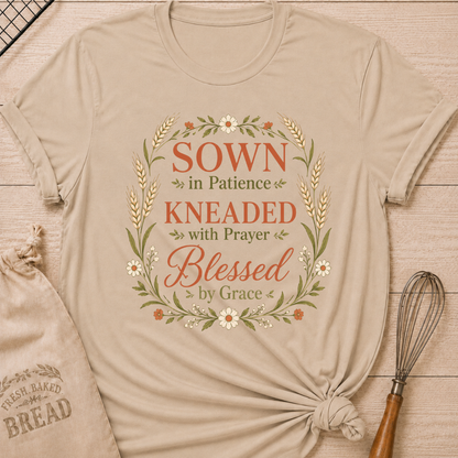 Heather stone women's relaxed fit t-shirt with the words Sown in Patience, Kneaded with Prayer, Blessed by Grace framed in wheat, daisies and delicate greenery.