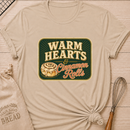 Heather stone women's relaxed fit t-shirt with the words Warm Hearts & Cinnamon Rolls in bold vintage lettering with a gooey iced cinnamon roll in a retro sign style.