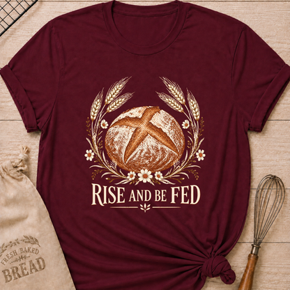 Maroon women's relaxed fit tee with a detailed artisan loaf framed by wheat and delicate wildflowers in a soft vintage style, above Rise and Be Fed lettering