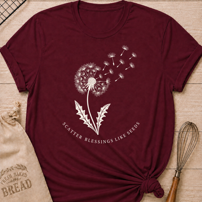 Maroon women's relaxed fit t-shirt with a dandelion releasing its seeds and the words Scatter Blessings Like Seeds.