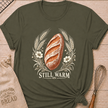 Military Green women's relaxed fit tee with a freshly baked artisan loaf framed by wheat and soft wildflowers in an old world engraved style, with Still Warm lettering