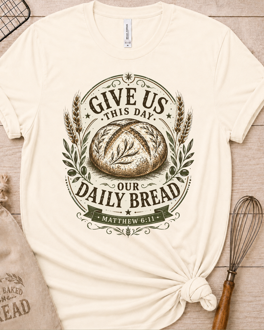Natural cream women's relaxed fit t-shirt with the Daily Bread emblem printed in cream, a clean badge-style bread illustration inspired by Matthew 6:11.
