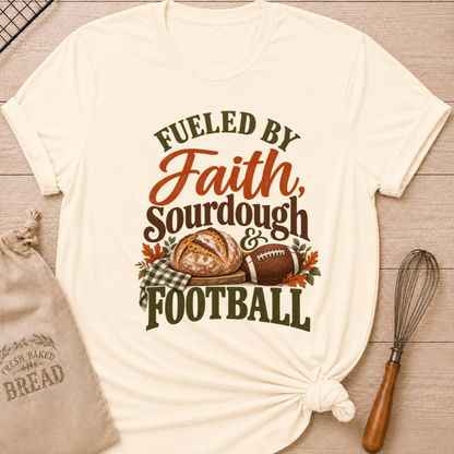 Natural women's relaxed fit tee with bold vintage Fueled by Faith Sourdough and Football lettering, a rustic sourdough loaf, classic football, gingham accents and autumn leaves