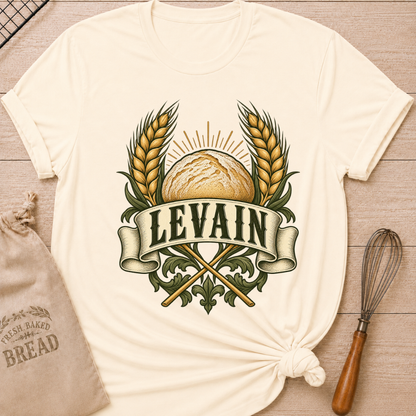 Natural women's relaxed fit tee with a rustic loaf between golden wheat and radiant accents, with Levain lettering on an old-world banner